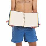 Closeup on young man in shorts showing blank photo album