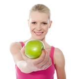Healthy teenager offering green apple to you