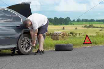 Man changing tire on the road