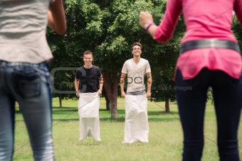 men playing sack race with girlfriends cheering