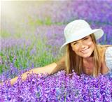 Beautiful happy female lying down on lavender field