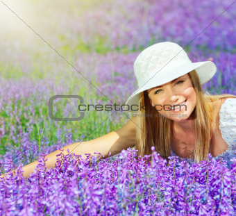 Beautiful happy female lying down on lavender field