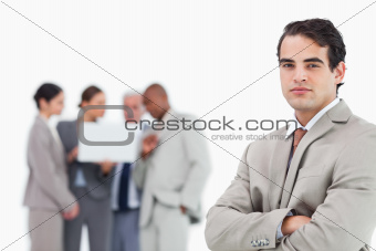 Businessman with arms folded and team behind him
