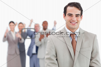 Smiling salesman with cheering team behind him