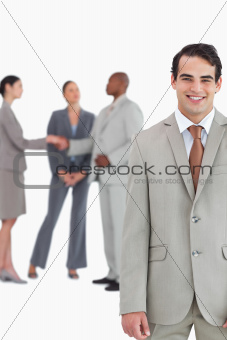 Smiling tradesman with businesspeople behind him