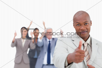 Businessman with cheering team behind him giving approval