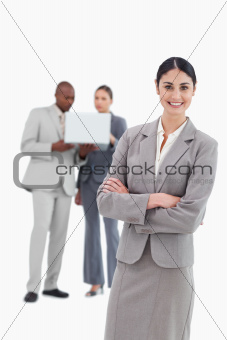 Smiling tradeswoman with folded arms and co-workers behind her