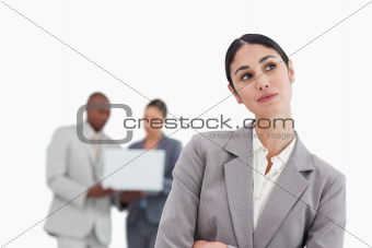 Daydreaming businesswoman with colleagues behind her