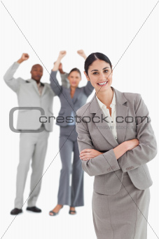 Smiling businesswoman with cheering colleagues behind her
