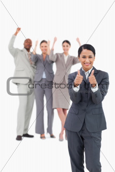 Saleswoman with cheering team behind her giving thumbs up