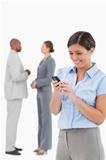 Businesswoman looking at cellphone with associates behind her