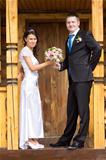 The bride and groom with a bouquet in a wooden porch