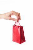 female hand holding red gift bag with present with her fingers -