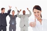 Saleswoman with cheering colleagues giving thumb up