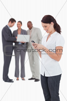 Saleswoman with mobile phone and colleagues behind her