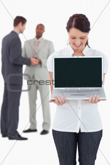 Businesswoman showing notebook with colleagues behind her