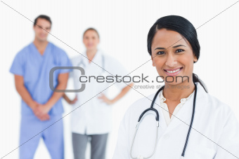 Smiling female doctor with colleagues behind her