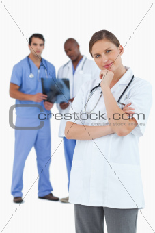 Doctor in thinkers pose with colleagues behind her