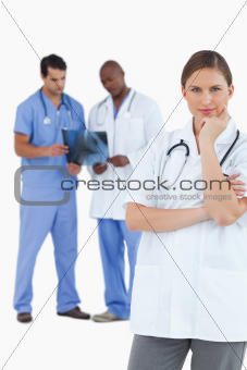 Thinking doctor with colleagues behind her