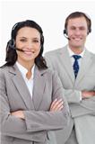 Smiling call center agents with headsets and arms folded