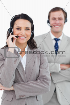 Smiling call center agents with headsets on and arms folded