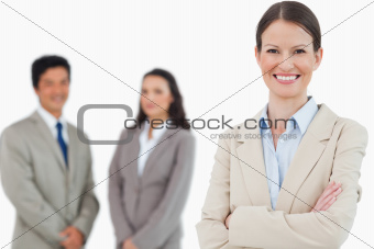 Smiling saleswoman with arms folded and associates behind her