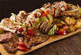 Rustic tray with various meats, mushrooms and assorted vegetables - isolated