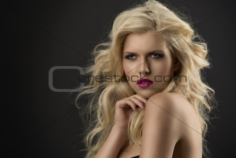 beauty portrait of blonde girl with hand near the chin