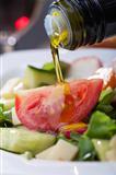 pouring olive oil over salad 