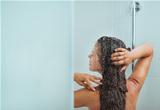 Woman with long hair taking shower. Rear view