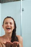 Happy woman catching water drops in shower under water jet