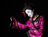 Portrait of geisha presenting something isolated on black