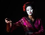 Portrait of geisha showing on something isolated on black