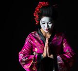 Portrait of geisha with hands together respect gesture isolated on black