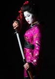 Portrait of geisha warrior pulls out sword of sheath on black