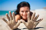A girl shows a hand in the sand