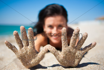 A girl shows a hand in the sand