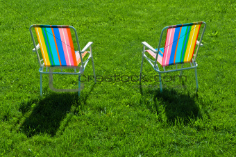 Two colorful chairs standing on grass