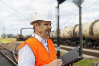 Engineer with folder at the station near the wagons