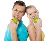 Young couple posing back to back with green apples