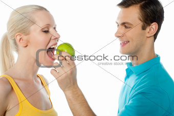 Young guy making her girlfriend eat an apple