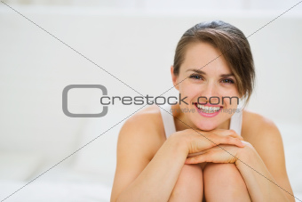 Portrait of happy woman sitting on bed