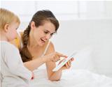 Young mother showing baby something in tablet PC