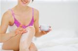 Closeup on healthy woman applying creme on leg in bed
