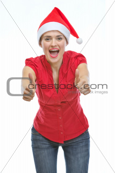 Smiling young woman in Christmas hat showing thumbs up