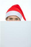 Female in Christmas hat hiding behind blank billboard