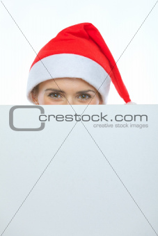 Female in Christmas hat hiding behind blank billboard