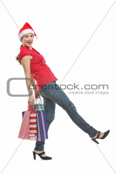 Happy woman in Christmas hat with shopping bags making step