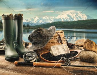Fly fishing equipment on deck with view of a lake and mountains