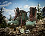 Pair of hiking boots with compass on fallen tree